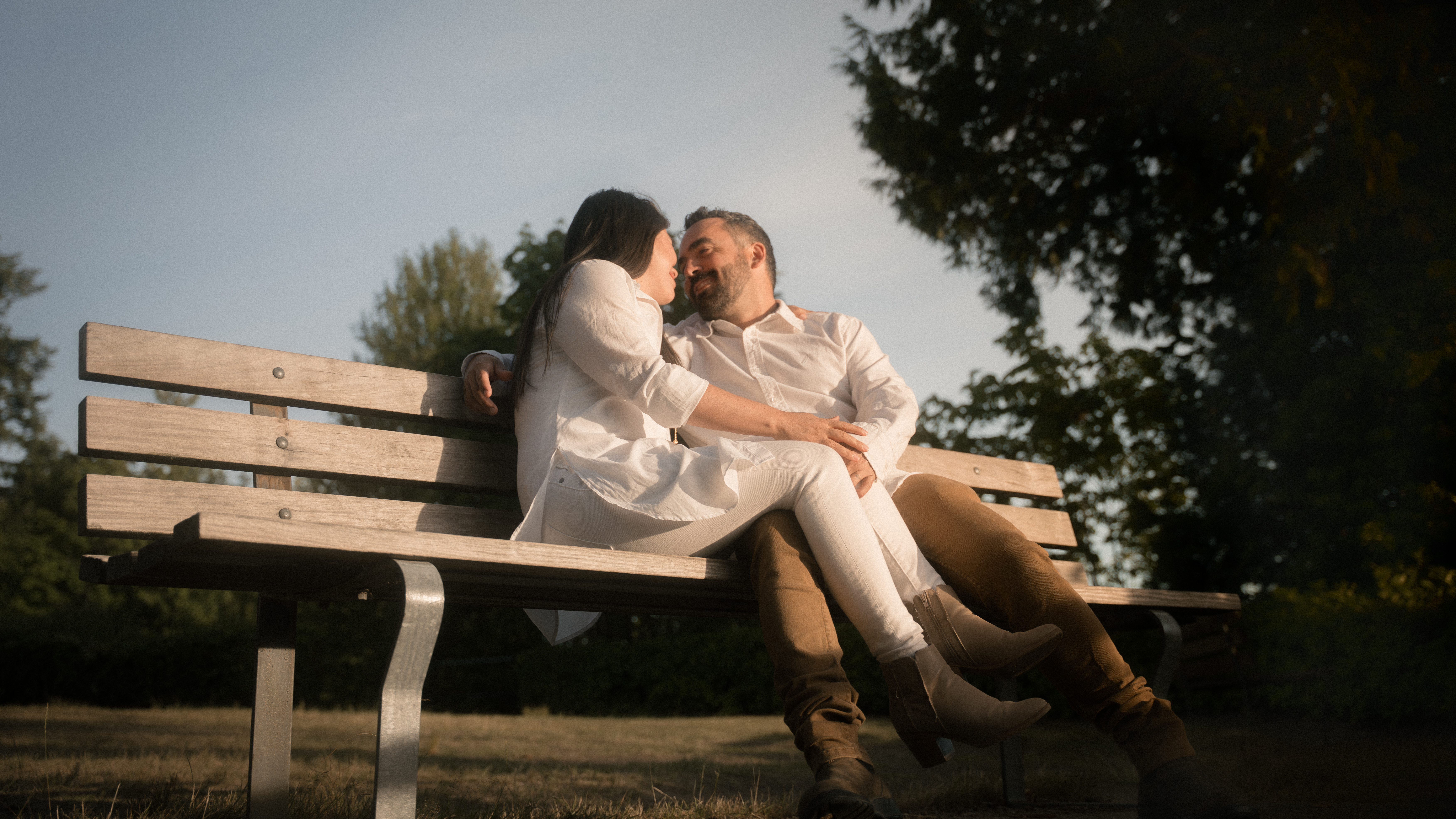 A couple sharing a quiet moment together on a park bench in evening light
