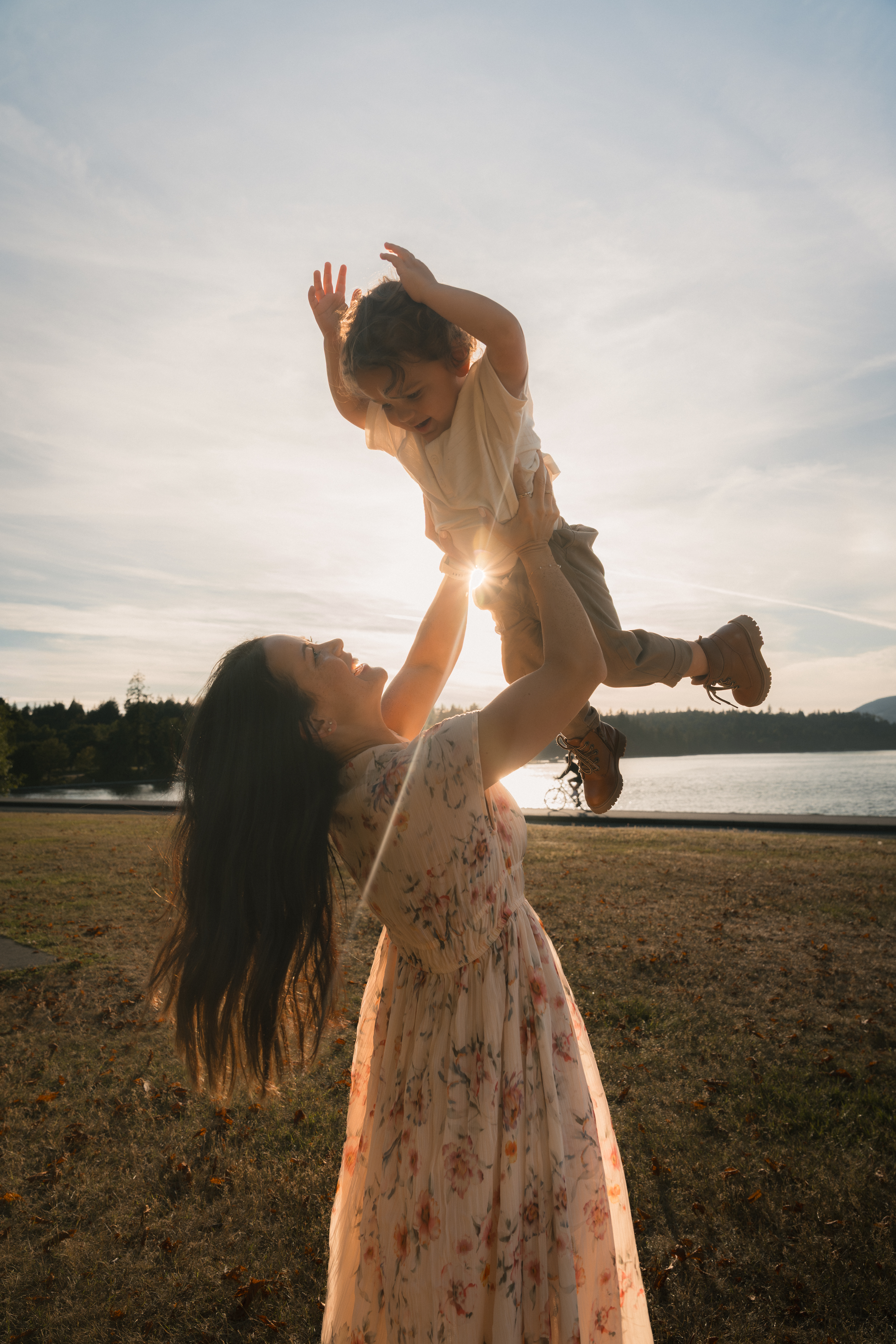 A mother lifting her child into the glowing evening sky