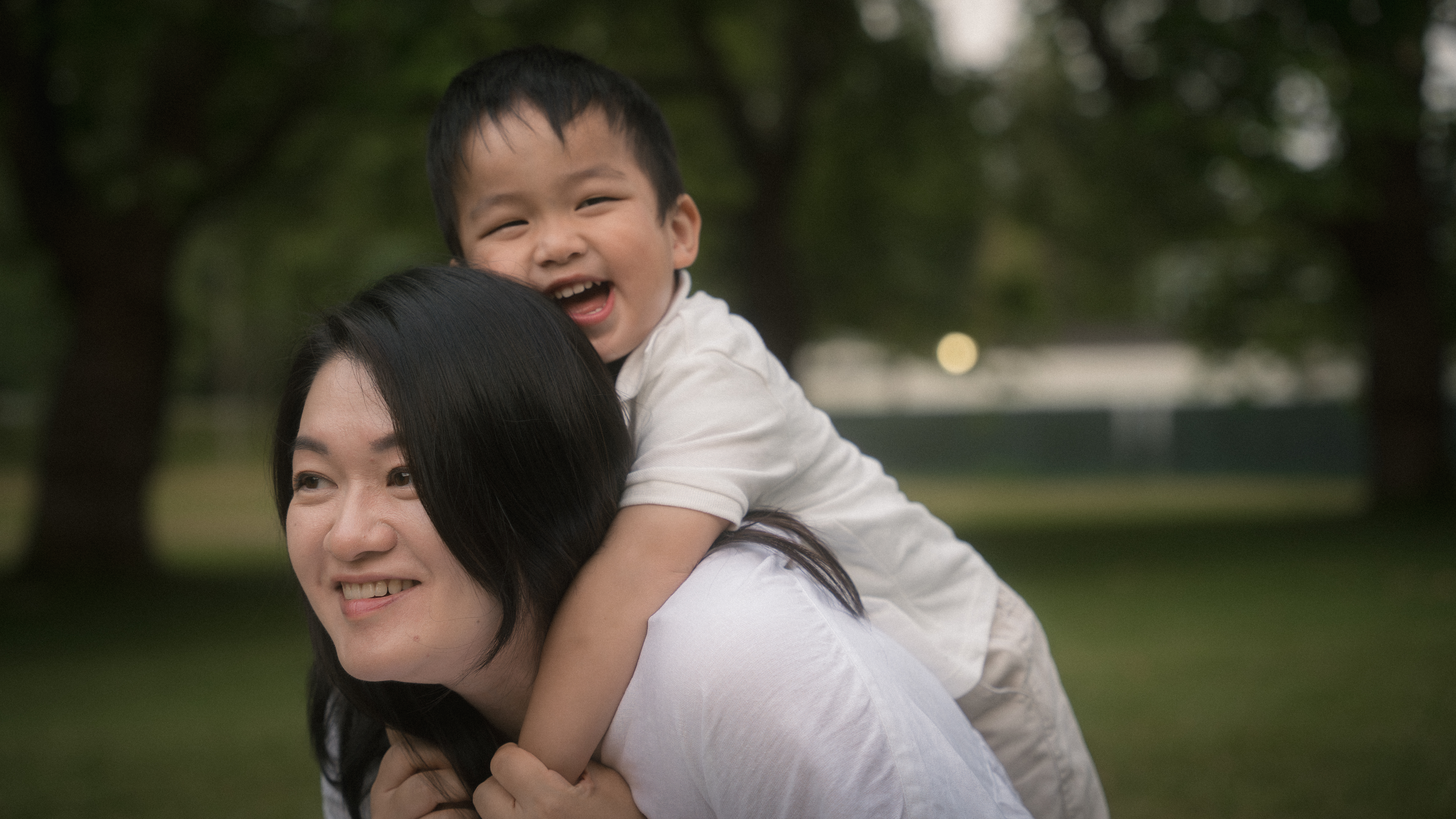 A smiling child riding on their mother's back